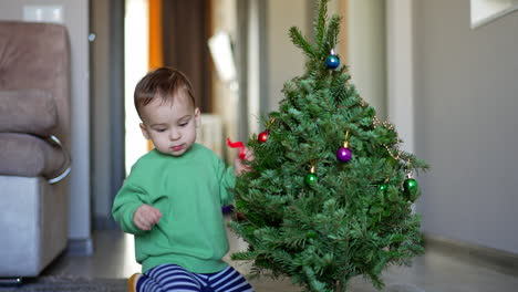 baby decorating a small christmas tree