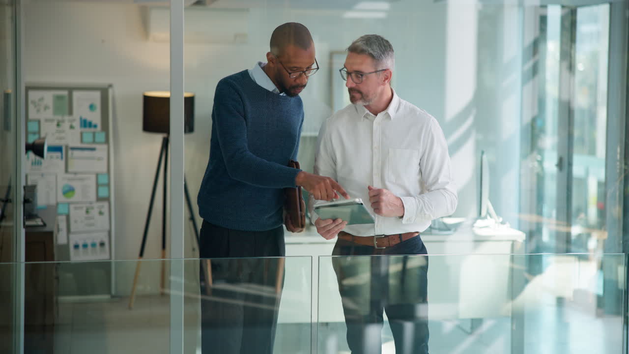 Two Businessmen Discussing Information on a Digital Tablet in a Modern Office