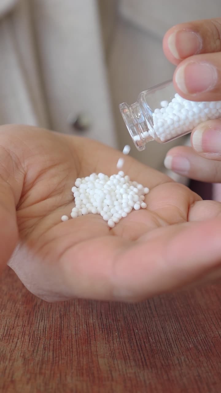 Pouring Small White Homeopathic Pellets into a Hand