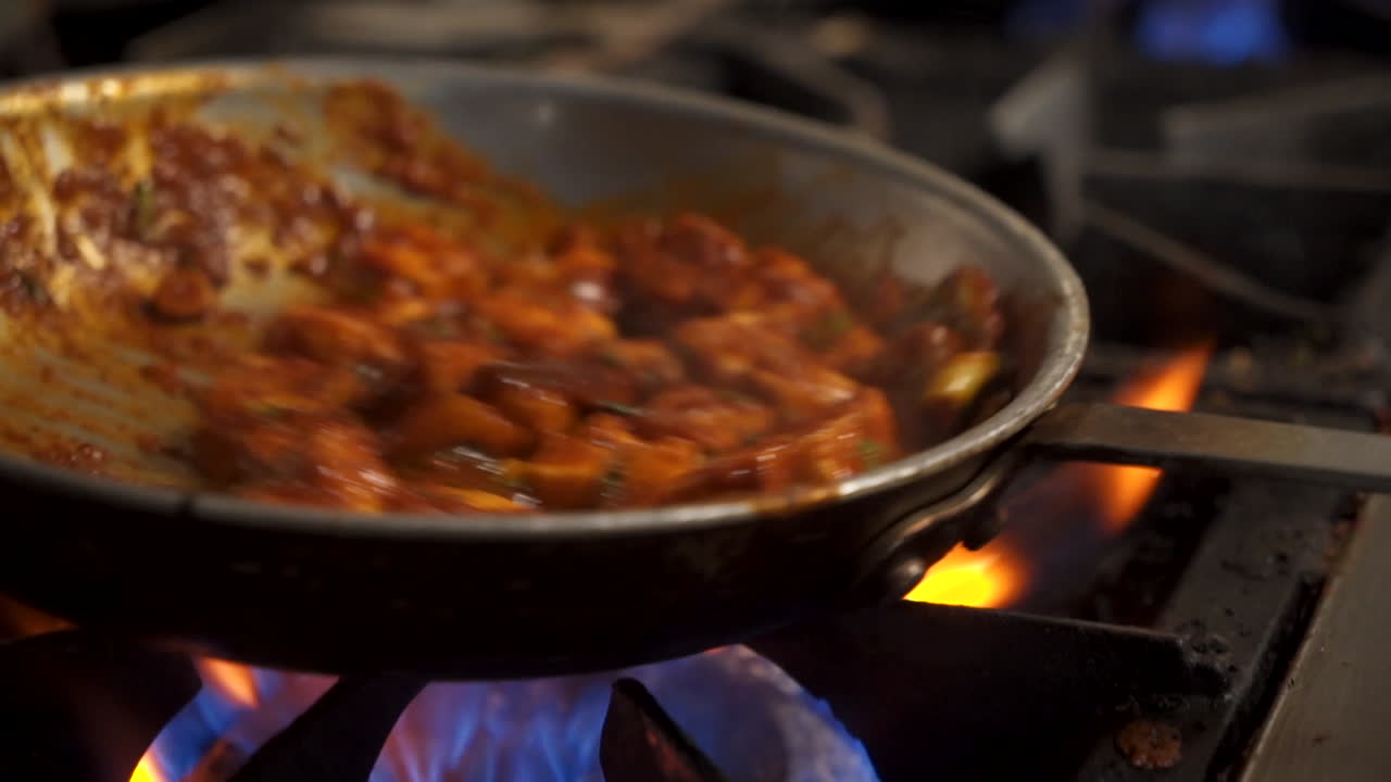 el chef lanza el paneer tradicional tikka masala sobre las llamas, cierra la cámara lenta 4k