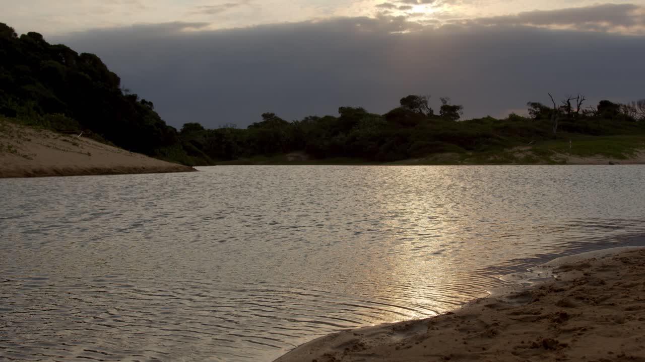 lapso de tiempo del sol poniéndose detrás de las nubes con arena de playa en primer plano