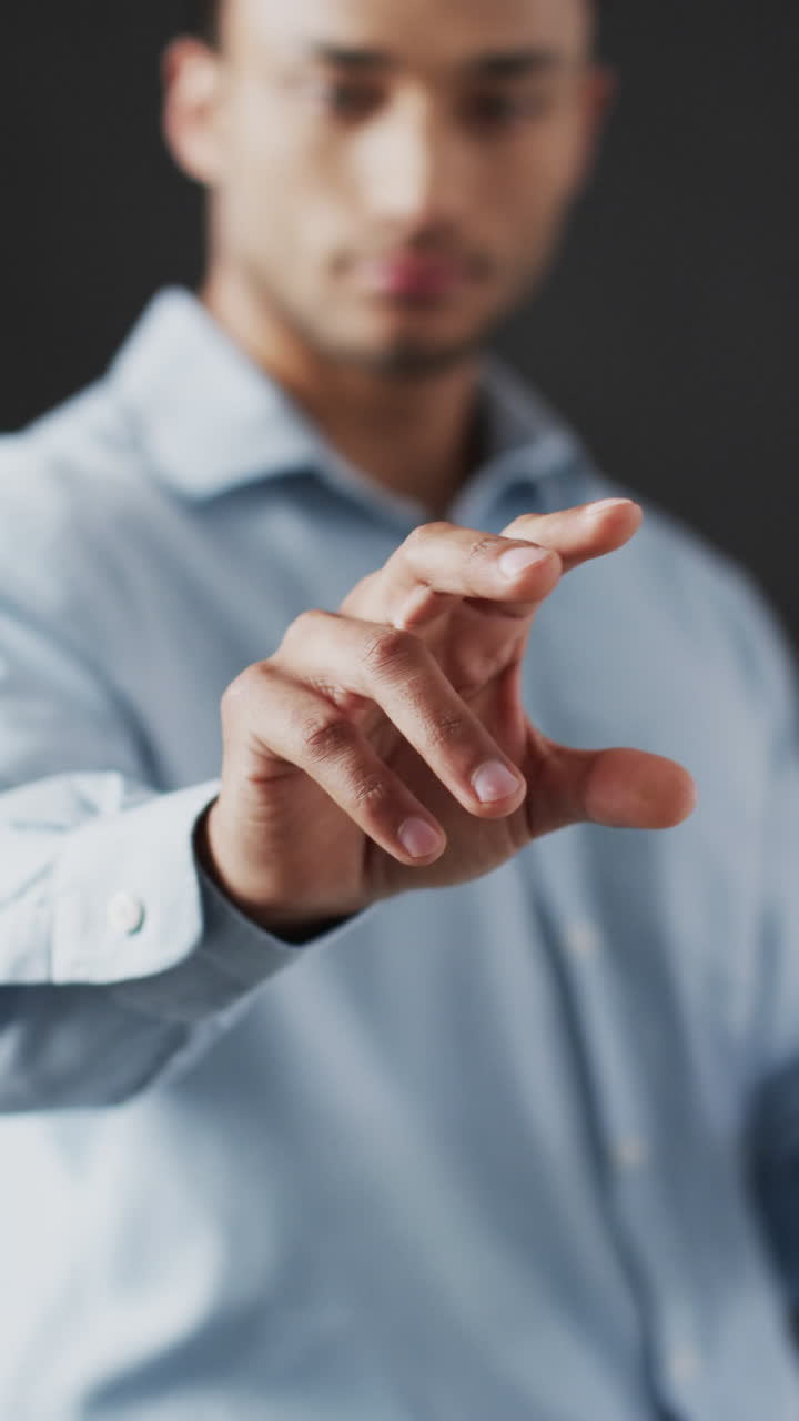 Video verticale di uomo d'affari birazziale che indica con il dito, utilizzando un display olografico, con spazio per il testo.
