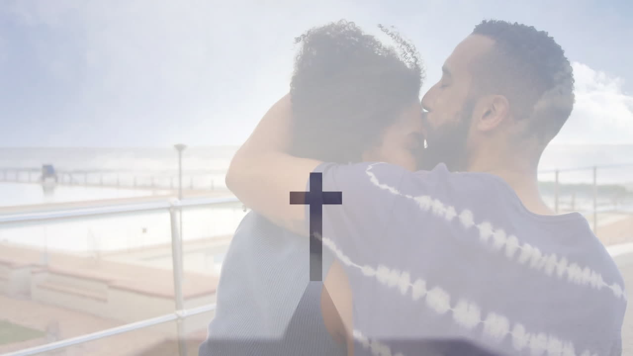 Embracing couple at seaside with cross symbol and animation overlay