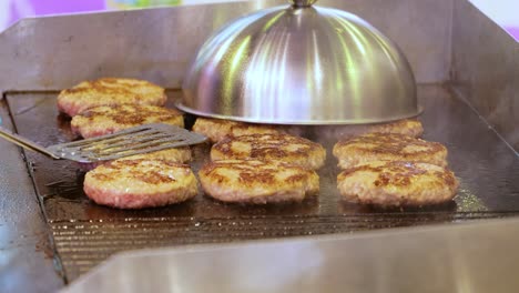 meat beef patty is cooked in a hot frying pan. street food, chef flips burgers with a spatula.