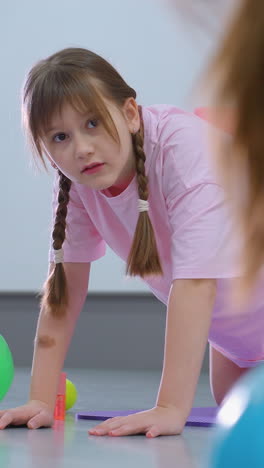 primer plano de una mujer entrenando a un niño pequeño que lleva un bloque rosa en la cintura durante una sesión de fitness, el niño intensamente centrado en la orientación del instructor