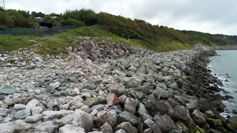 lush rocky north wales hillside shoreline ocean boulders aerial view low angle reverse