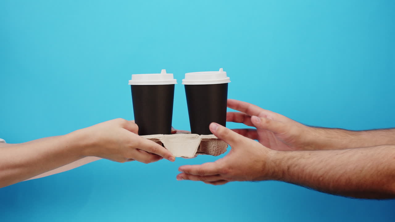 Hænder rækker to kaffekopper i papkopholder