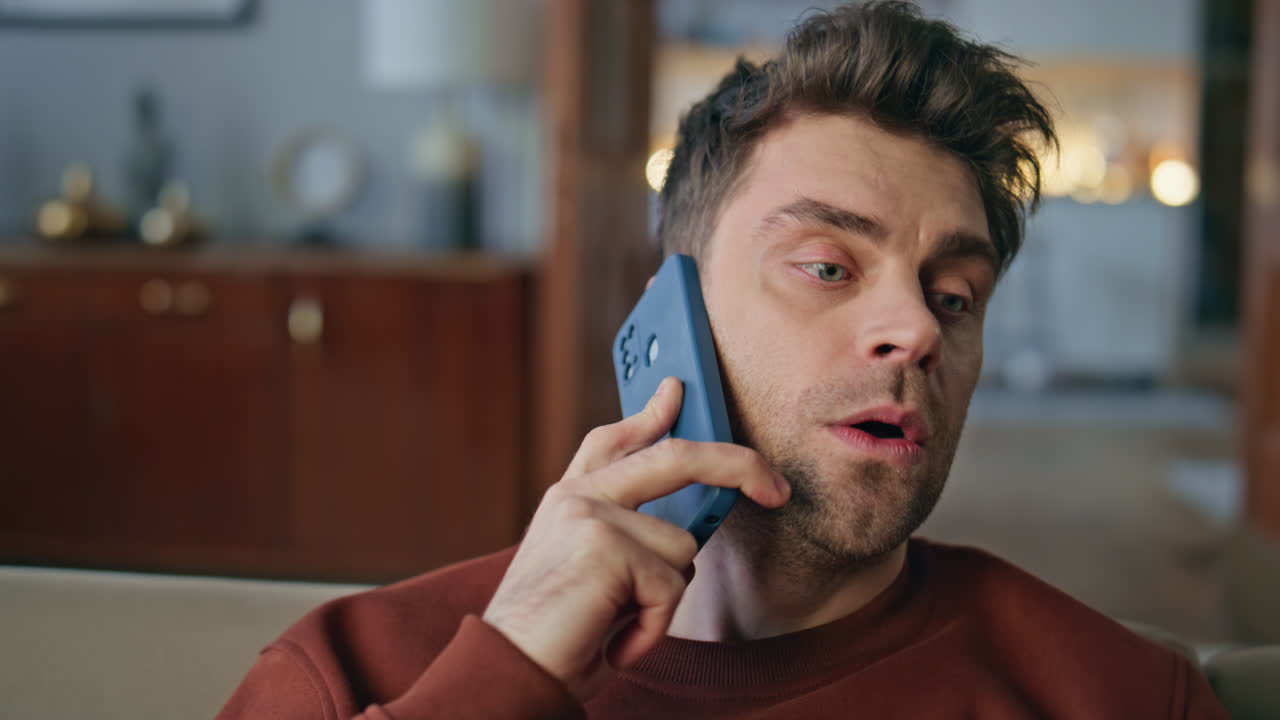 Uomo preoccupato che parla al telefono in appartamento, primo piano. Ritratto di uomo serio al telefono.