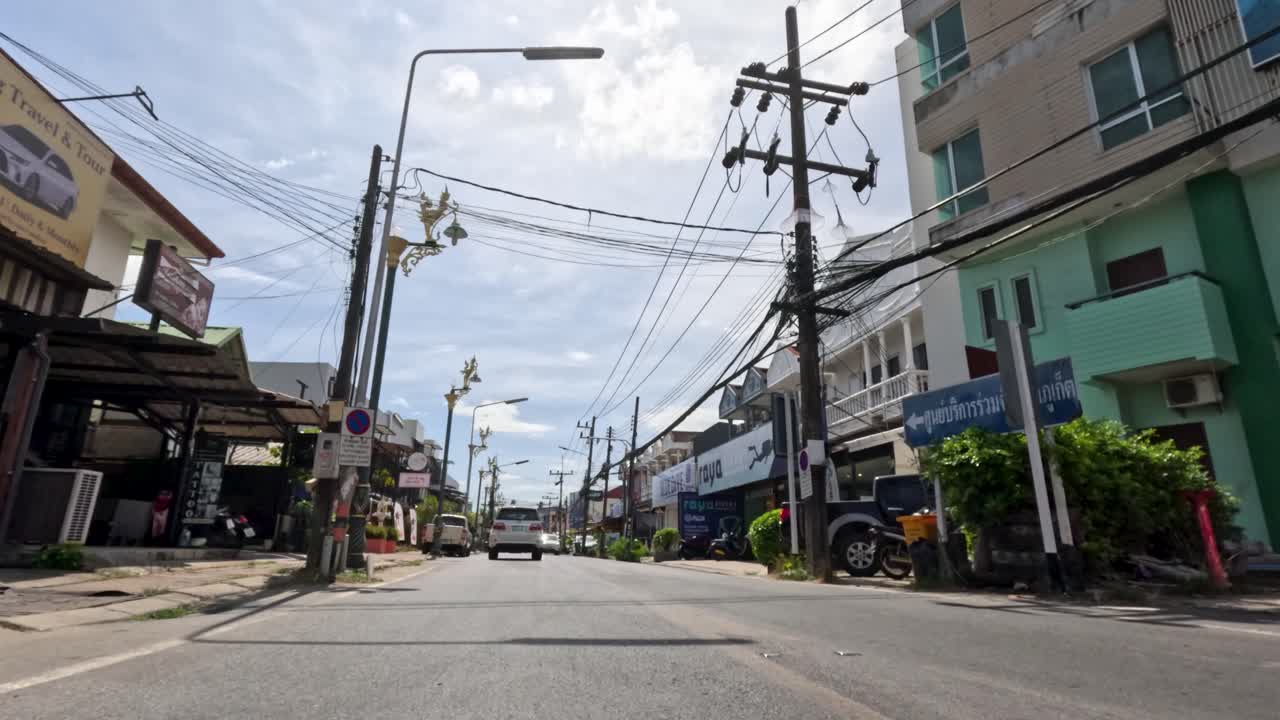 Vehicles and scooters navigate busy Phuket streets, tropical urban environment, daylight, wide-angle perspective