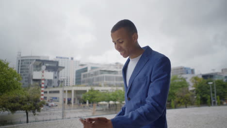 Emotional-African-American-young-man-with-smartphone-outdoor.