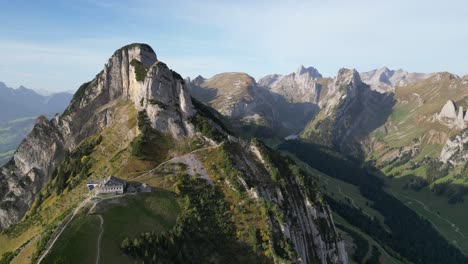 Drone-shot-over-a-mountain-range-with-a-mountain-guest-house-on-the-top-of-the-rock