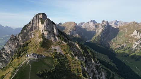 drone shot over a mountain range with a mountain guest house on the top of the rock