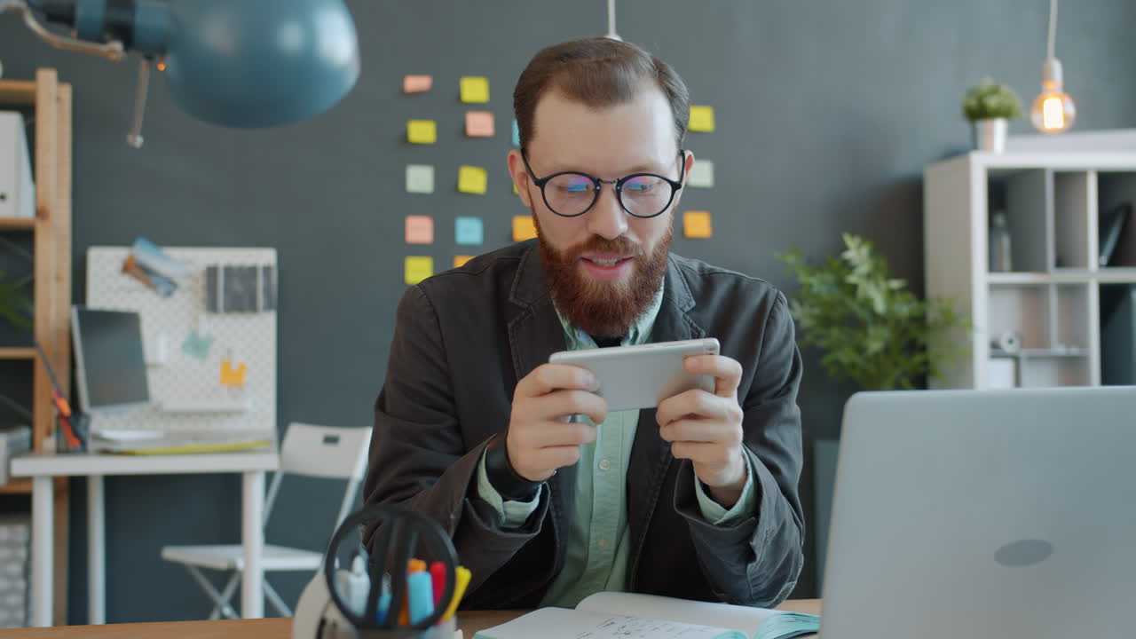 Businessman Playing Mobile Game in Office