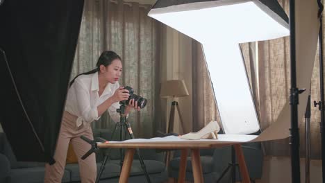 asian female photographer thinking while taking photos of them in home studio