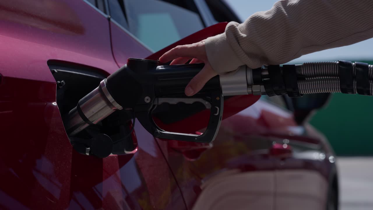 Close-up Tangan Mengisi Bahan Bakar ke Mobil Merah