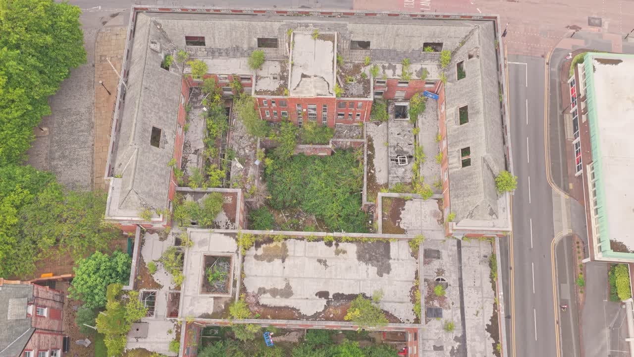 Aerial top view of the derelict Salford Crescent Police Station, its courtyard overgrown with vegetation, showing the decay and urban transformation of this once-important civic building