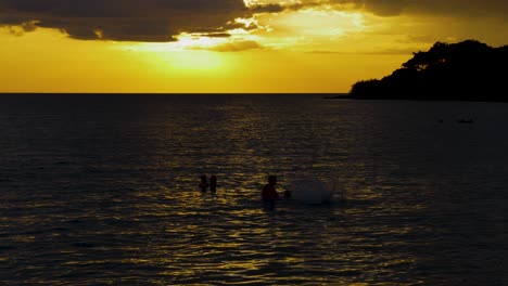 silhouettes of family playing in the sea at dusk