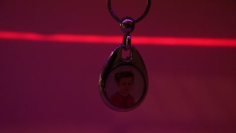 close up of the hanging child's photo in metal souvenir keychain and the moving laser light