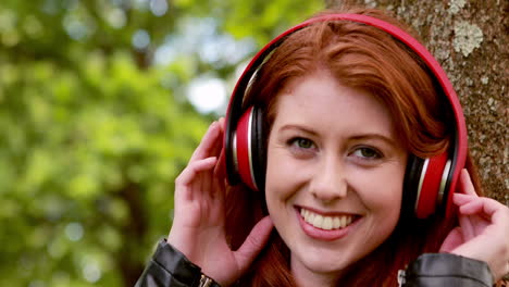 Pretty-redhead-listening-to-music-in-the-park-