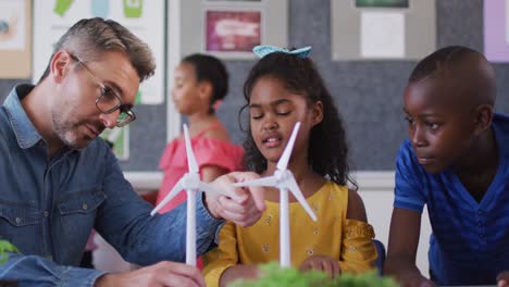 maestro y niños diversos, aprendiendo sobre la energía eólica y las fuentes renovables de energía