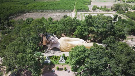 giant buddha surrounded by trees in wat preah theat thmor da temple - kampong cham drone aerial fly over