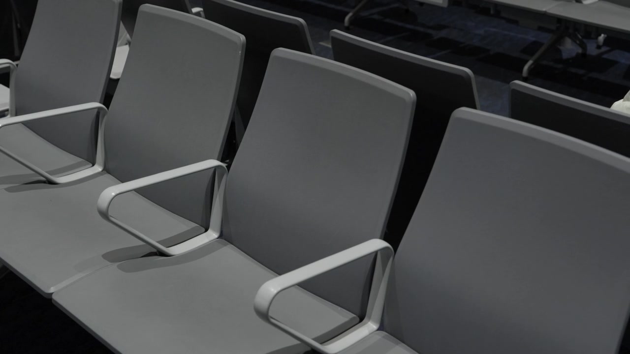 Fila de asientos grises vacíos con reposabrazos en la zona de espera de la terminal del aeropuerto