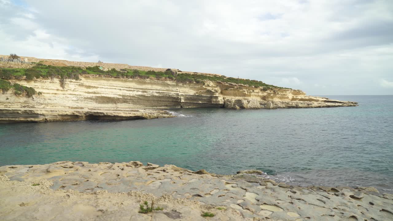 el tranquilo mar mediterráneo lava la orilla de piedra caliza de la playa de piedra il-kalanka en malta