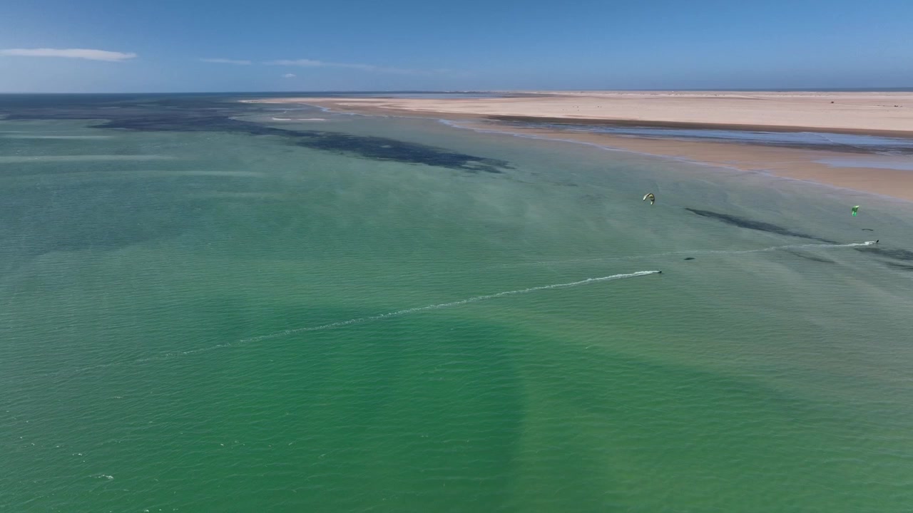 Bred drone-luftfoto af Dakhla-bugten med turkise tidevandsfarvande, sandede landtangeformationer og uberørte kystørkenlandskaber i det sydlige Marokko. Ideel til rejse- og naturdokumentarer