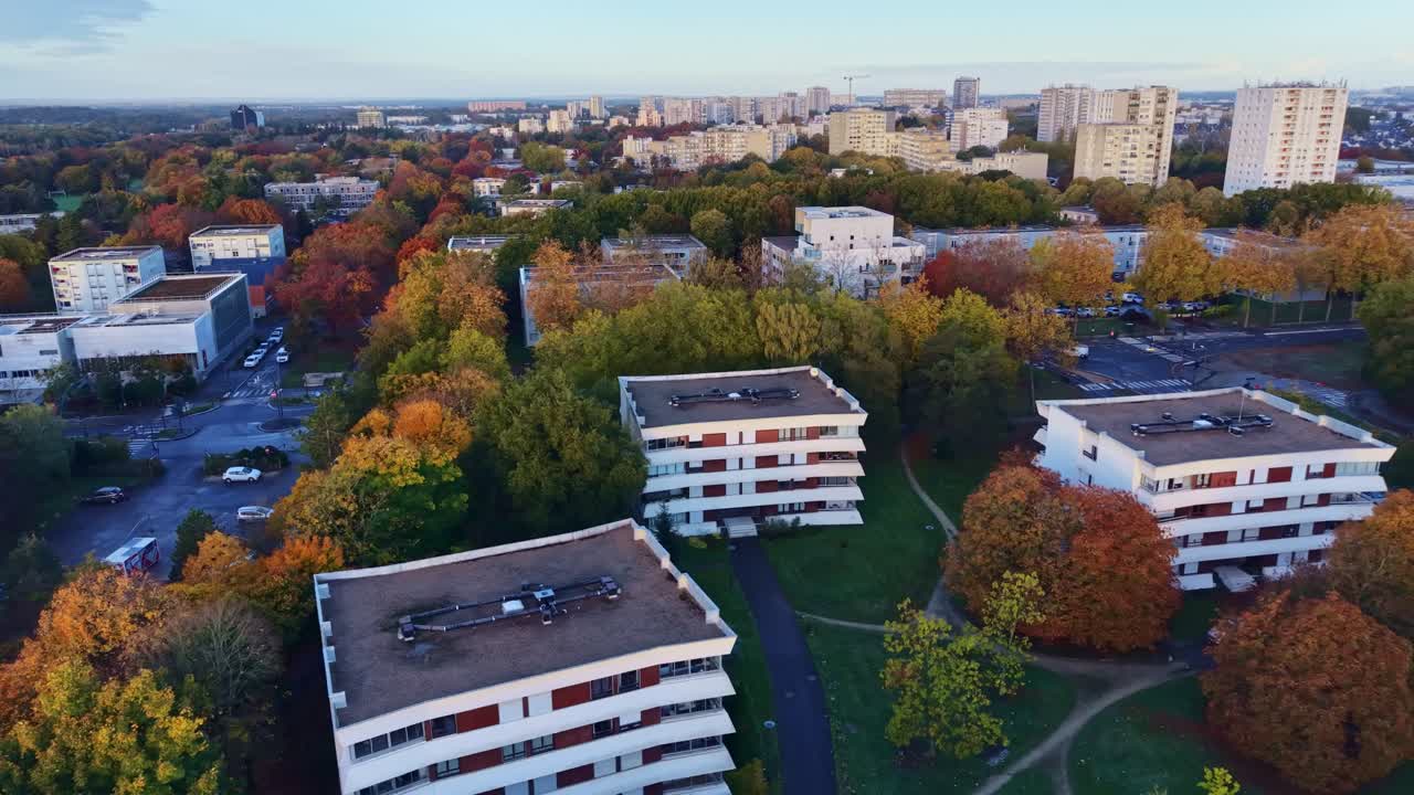 Moderni condomini circondati da alberi autunnali colorati nel quartiere Le Blosne di Rennes, Francia. Ripresa aerea con drone in avanti.