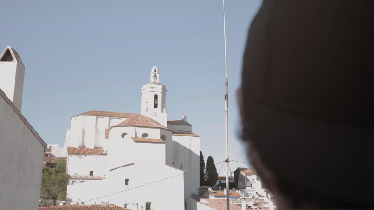 unidentified man seeing old tower with clock and iconic building in Roses, Costa Brava, Catalonia, Spain