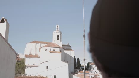 unidentified man seeing old tower with clock and iconic building in roses, costa brava, catalonia, spain