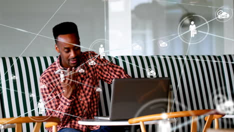 animation of network of profile icons over african american man talking on smartphone at office