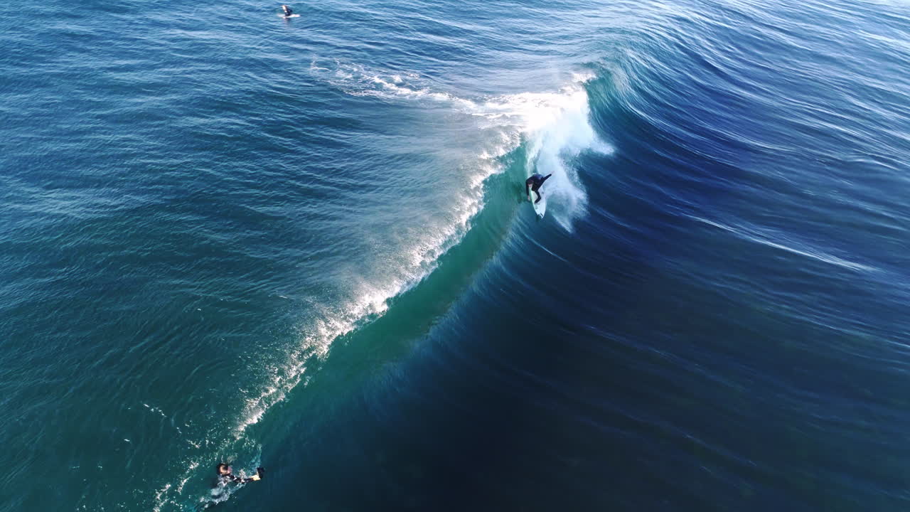 Turquoise ocean barrel curls over surfer pulling in as white spray explodes outward, aerial slow motion