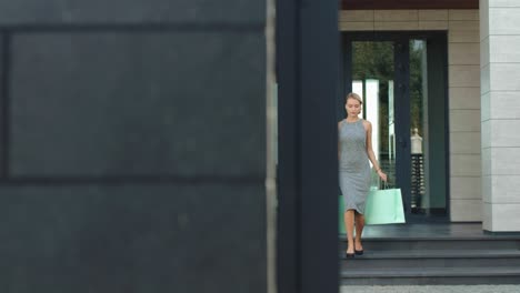 Beautiful-woman-going-down-stairs-from-clothes-shop-with-shopping-bags.