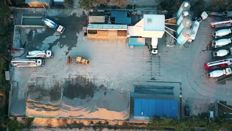 Aerial-view-of-a-semi-trucks-with-cargo-trailers-standing-on-warehouses-ramps-for-loading-unloading-goods-on-the-big-logistics-park-with-loading-hub