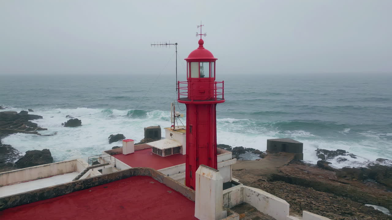 Drone view lighthouse tower placed on gloomy seashore. Ocean waves landscape