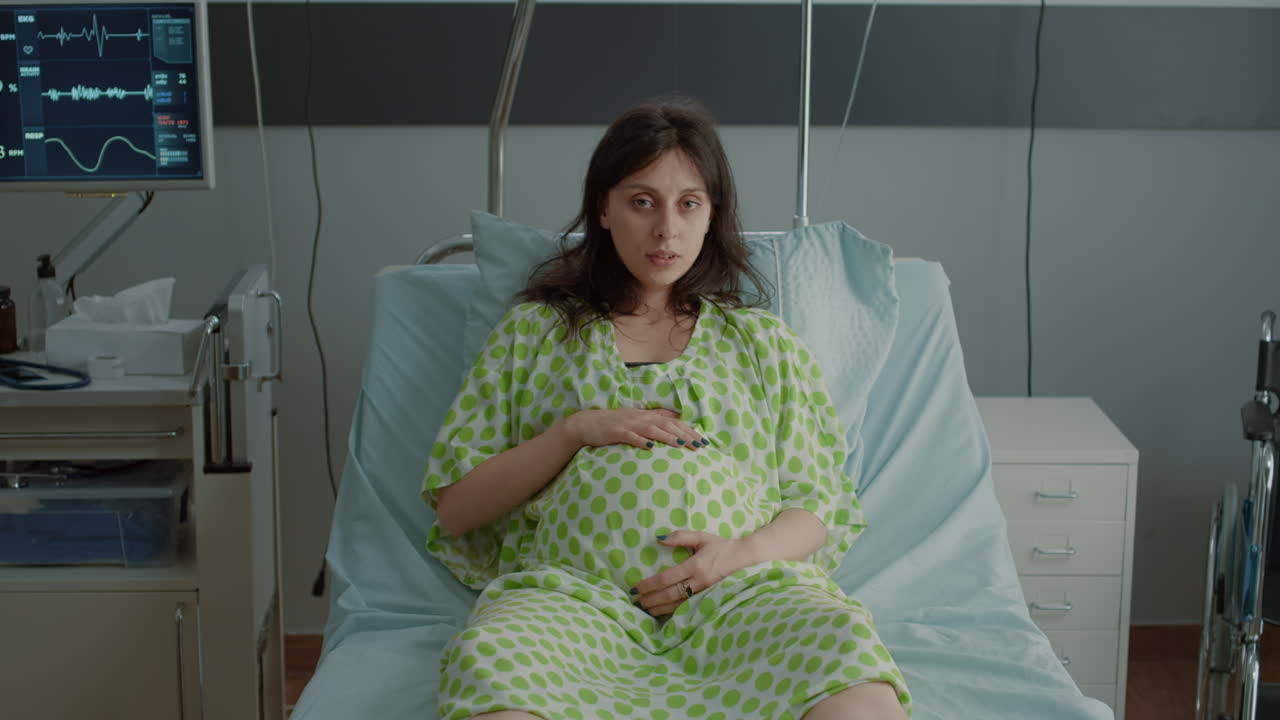 Portrait of pregnant woman laying in hospital ward bed