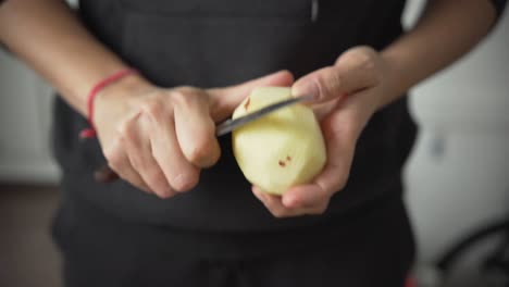 woman hands peeling a potato with a knife, cooking fresh organic vegetables