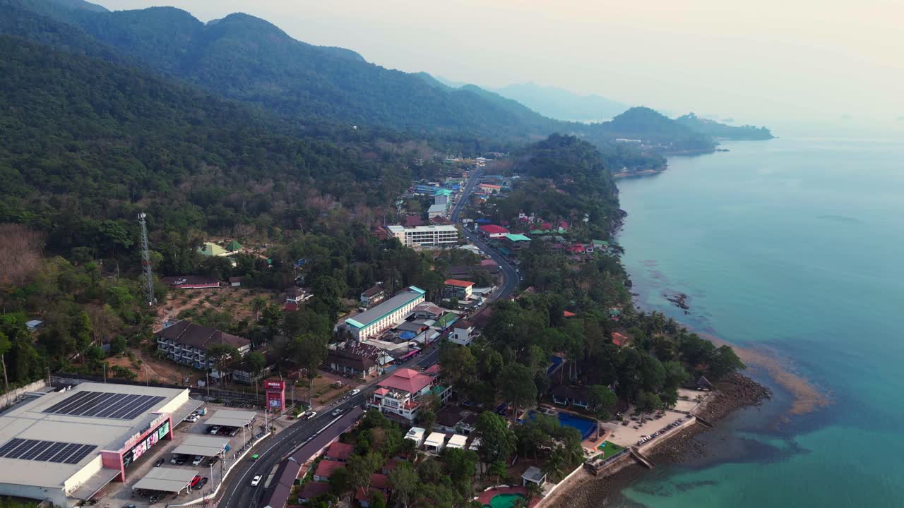 Road on Koh Chang, White Sand Beach Village, lush green hills. Dramatic aerial view flight drone shot footage from above