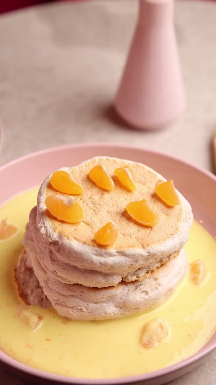 colocando a mano rebanadas de naranja en panqueques apilados con salsa de crema