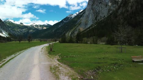 cierra el vuelo de un dron a lo largo de un banco y un árbol en el valle montañoso de ahornboden a lo largo del río rissach con agua azul fresca en los alpes austríacos bávaros en un día nublado y soleado a lo largo del bosque y las colinas