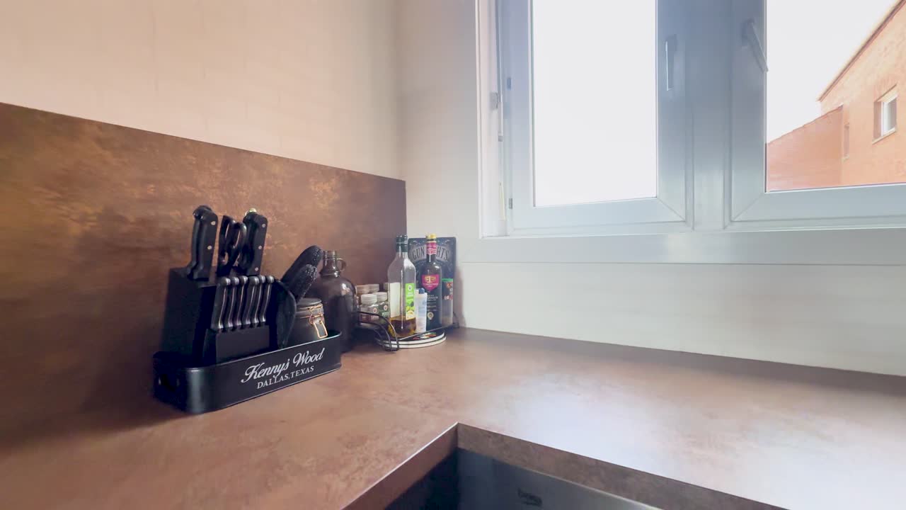 Smooth pan reveals bright modern kitchen with retro accents, sleek appliances, decor, and daylight