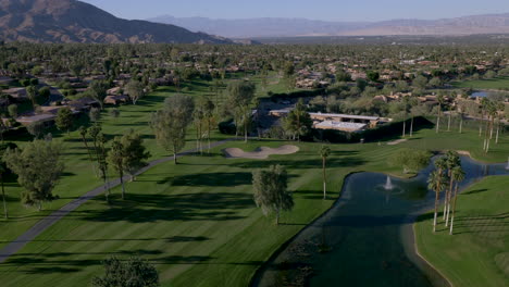 aerial view of a sprawling desert golf course with palm trees, ponds, and a residential community