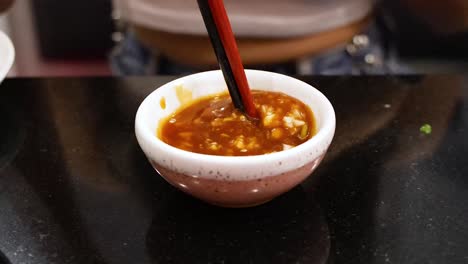 palillos para comer moviendo la salsa en un cuenco pequeño