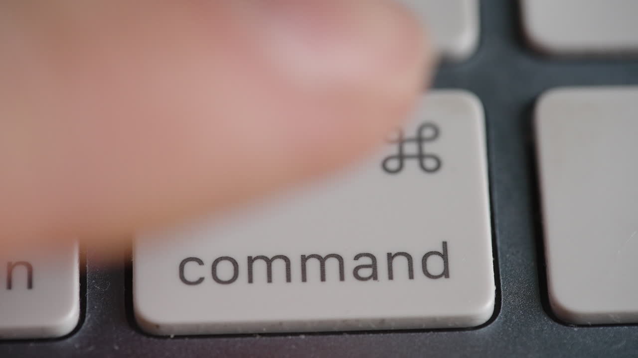 Extreme close up of a finger pressing the command key on a white chiclet style keyboard. Ideal for technology, software development, and shortcut tutorials