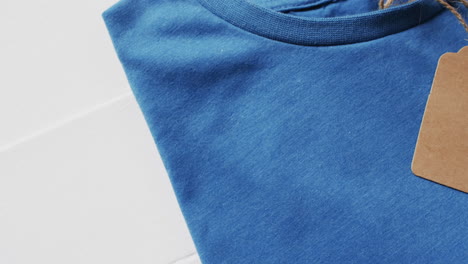 video de una capa plana de camiseta azul con etiqueta y espacio de copia sobre fondo blanco