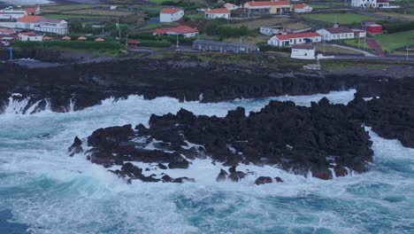 reveal shot of fajã grande town at flores island with rough sea, aerial