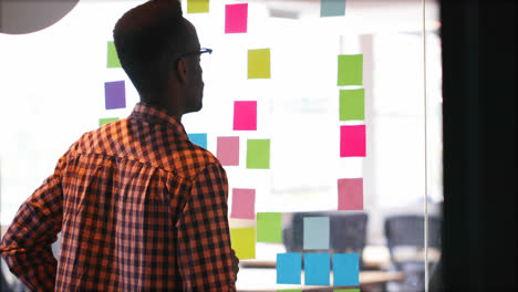 male executive checking sticky note on glass wall 4k