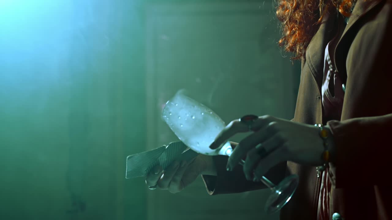 Fortune teller hands holding a cup with smoke and cards above a table with mysterious jewelry. Backstage and behind the scene. Side view. Cinematic view