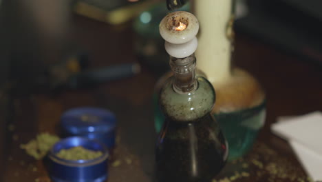 cannabis medicinal encendido y fumado a través de un bong de agua sucia